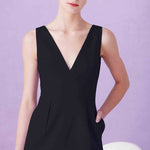 A professional woman showcasing two elegant sleeveless V-neck sheath dresses in classic black and soft lilac purple, featuring functional side pockets and a tailored fit for a polished office look.
