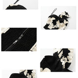 A professional woman wearing a sophisticated one-shoulder black and white floral print top, featuring a dramatic oversized bow detail on the shoulder, paired with white high-waisted trousers for an elegant evening look.