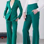 A professional woman wearing sophisticated emerald green high-waisted flare trousers, featuring a tailored slim fit through the hip and a stylish bootcut silhouette for an elegant office look.