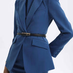 A professional woman wearing a sophisticated royal blue tailored skirt suit, featuring a slim-fit single-button blazer with structured shoulders and a matching midi pencil skirt for a powerful executive office look.