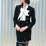 A chic woman wearing a luxurious black sparkle tweed tailored jacket featuring an authentic stand cheongsam collar, elegant horizontal pearl bar closures, and a flattering hourglass waistline.