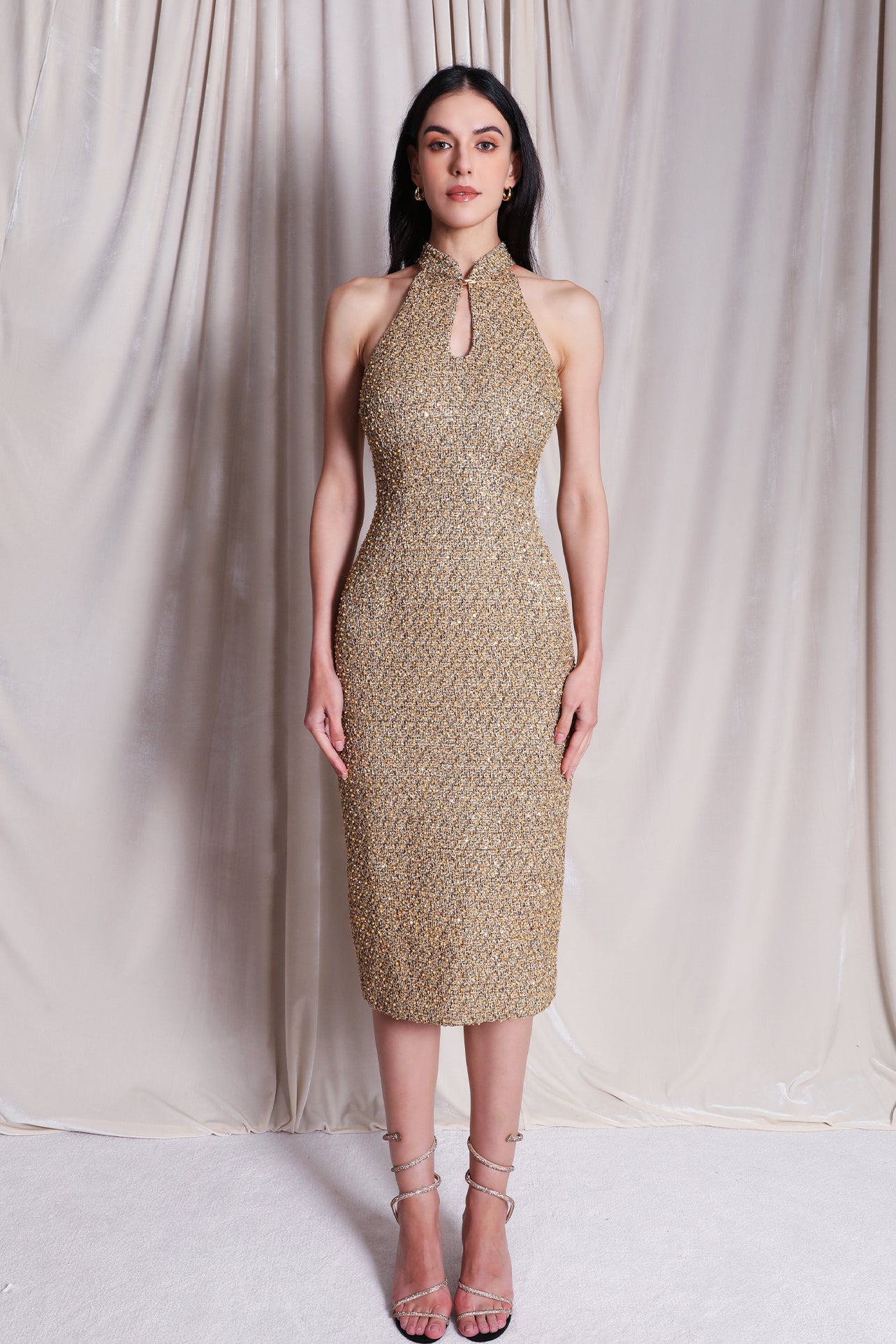 A stunning professional model wearing a luxurious gold sequined halter neck evening gown, featuring a sophisticated keyhole neckline and a slim-fit silhouette for a formal gala look.
