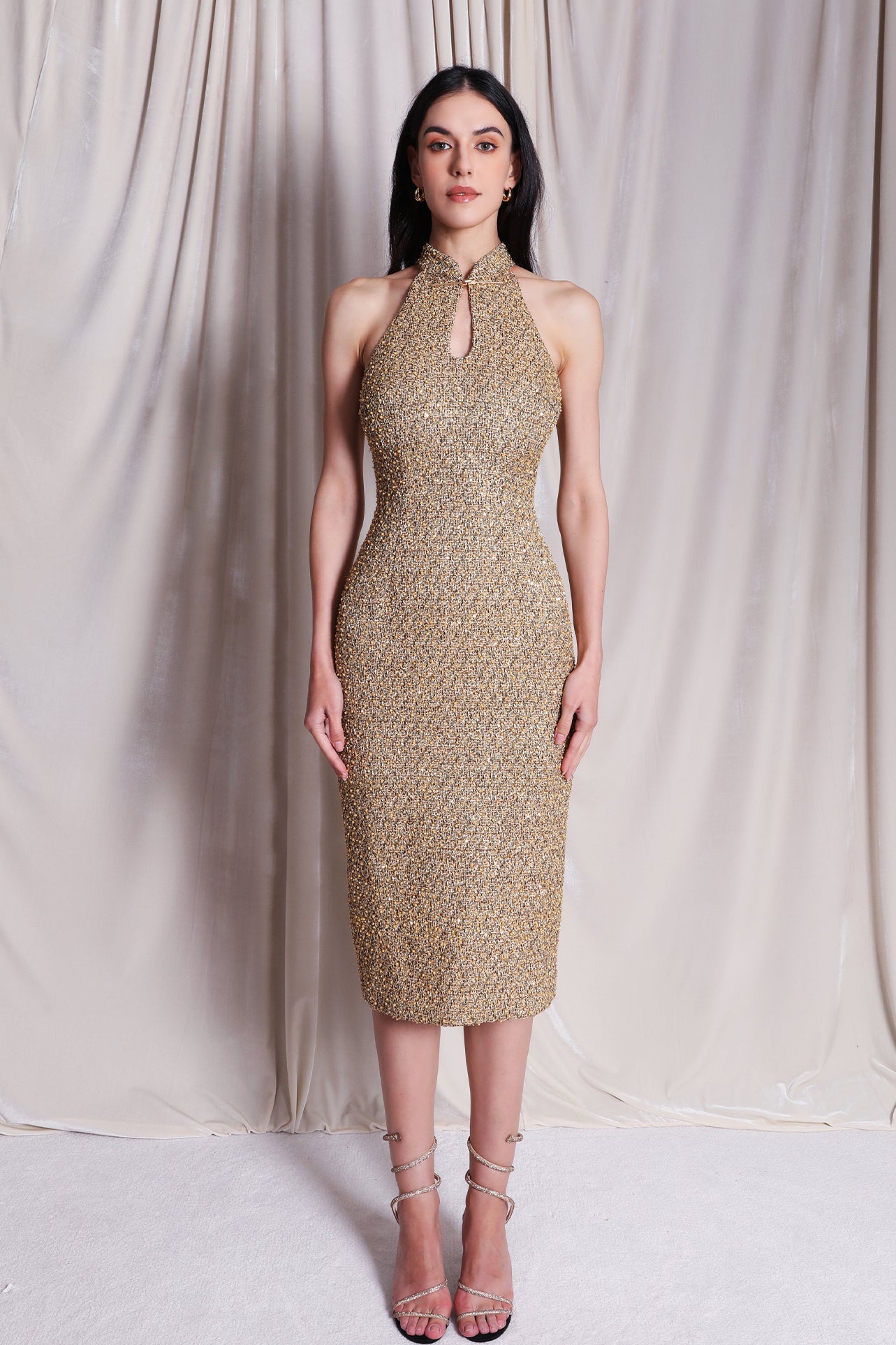 A stunning professional model wearing a luxurious gold sequined halter neck evening gown, featuring a sophisticated keyhole neckline and a slim-fit silhouette for a formal gala look.