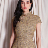 A professional woman wearing a stunning luxurious gold sequined modern qipao dress, featuring a traditional mandarin collar, short cap sleeves, and a slim-fit floor-length silhouette for a formal evening gala.