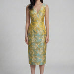 A professional woman wearing a stunning gold and teal jacquard sheath dress, featuring a sophisticated V-neckline and elegant artistic wave patterns for a high-end formal look.