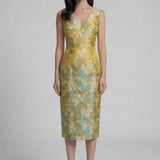 A professional woman wearing a stunning gold and teal jacquard sheath dress, featuring a sophisticated V-neckline and elegant artistic wave patterns for a high-end formal look.