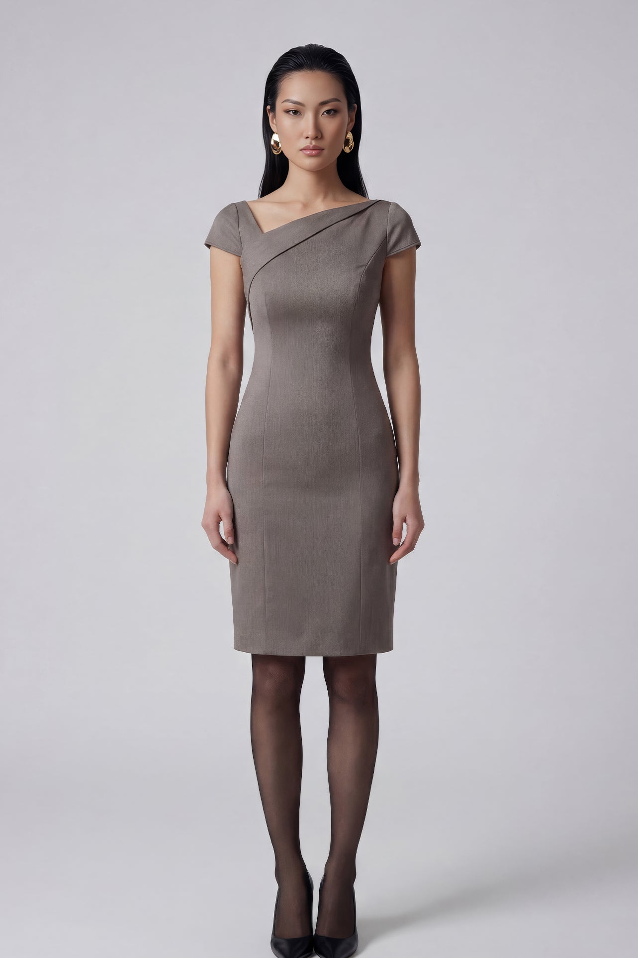 A professional woman wearing a sophisticated taupe grey sheath dress, featuring a chic asymmetric neckline, cap sleeves, and a tailored slim-fit silhouette for an elegant office look.