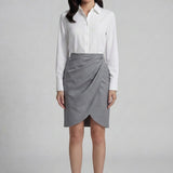A professional woman wearing a sophisticated grey pencil skirt, featuring an elegant tulip hem and flattering side ruched detailing for a polished office look.