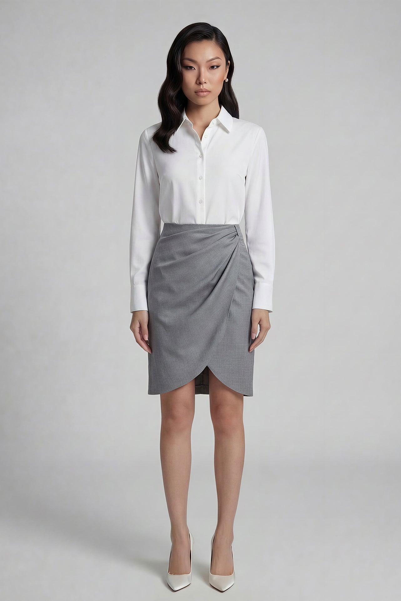 A professional woman wearing a sophisticated grey pencil skirt, featuring an elegant tulip hem and flattering side ruched detailing for a polished office look.