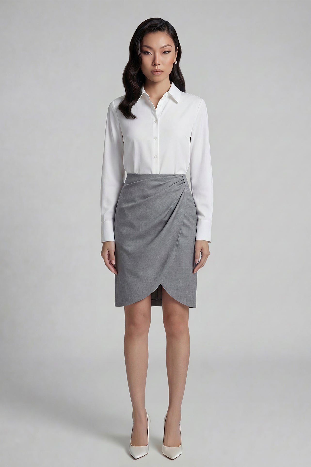 A professional woman wearing a sophisticated grey pencil skirt, featuring an elegant tulip hem and flattering side ruched detailing for a polished office look.