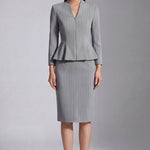A professional woman wearing a sophisticated grey pinstripe skirt suit, featuring a tailored zipper-front peplum jacket and a matching midi pencil skirt for a polished executive office look.