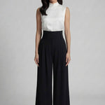 A professional woman wearing sophisticated black high-waisted wide-leg trousers, featuring a flattering high-rise fit and a flowing full-length silhouette for an elegant office look.