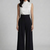 A professional woman wearing sophisticated black high-waisted wide-leg trousers, featuring a flattering high-rise fit and a flowing full-length silhouette for an elegant office look.