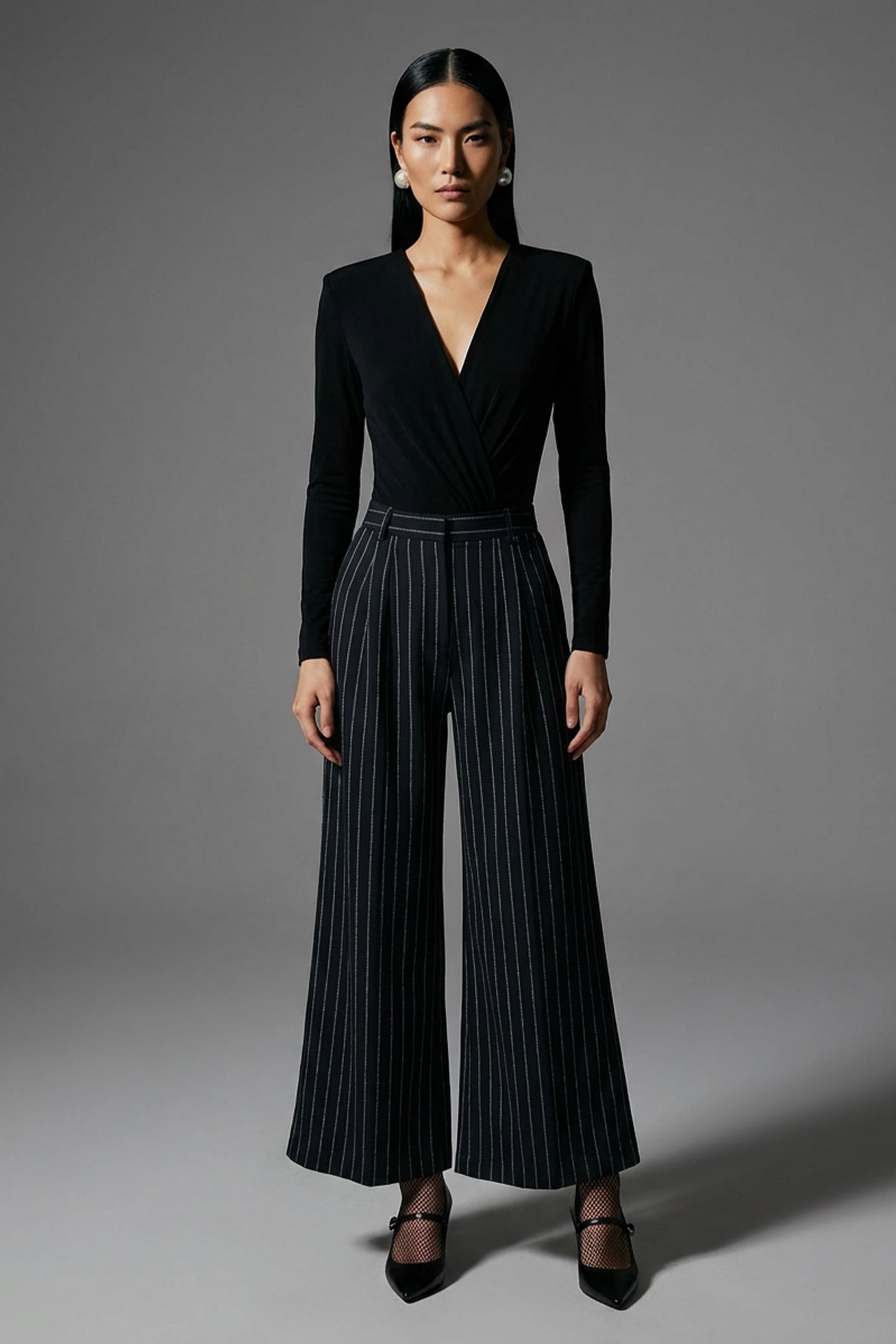 A professional woman wearing sophisticated navy blue pinstripe wide-leg trousers, featuring a high-waisted tailored fit and elegant vertical stripes for a polished executive office look.