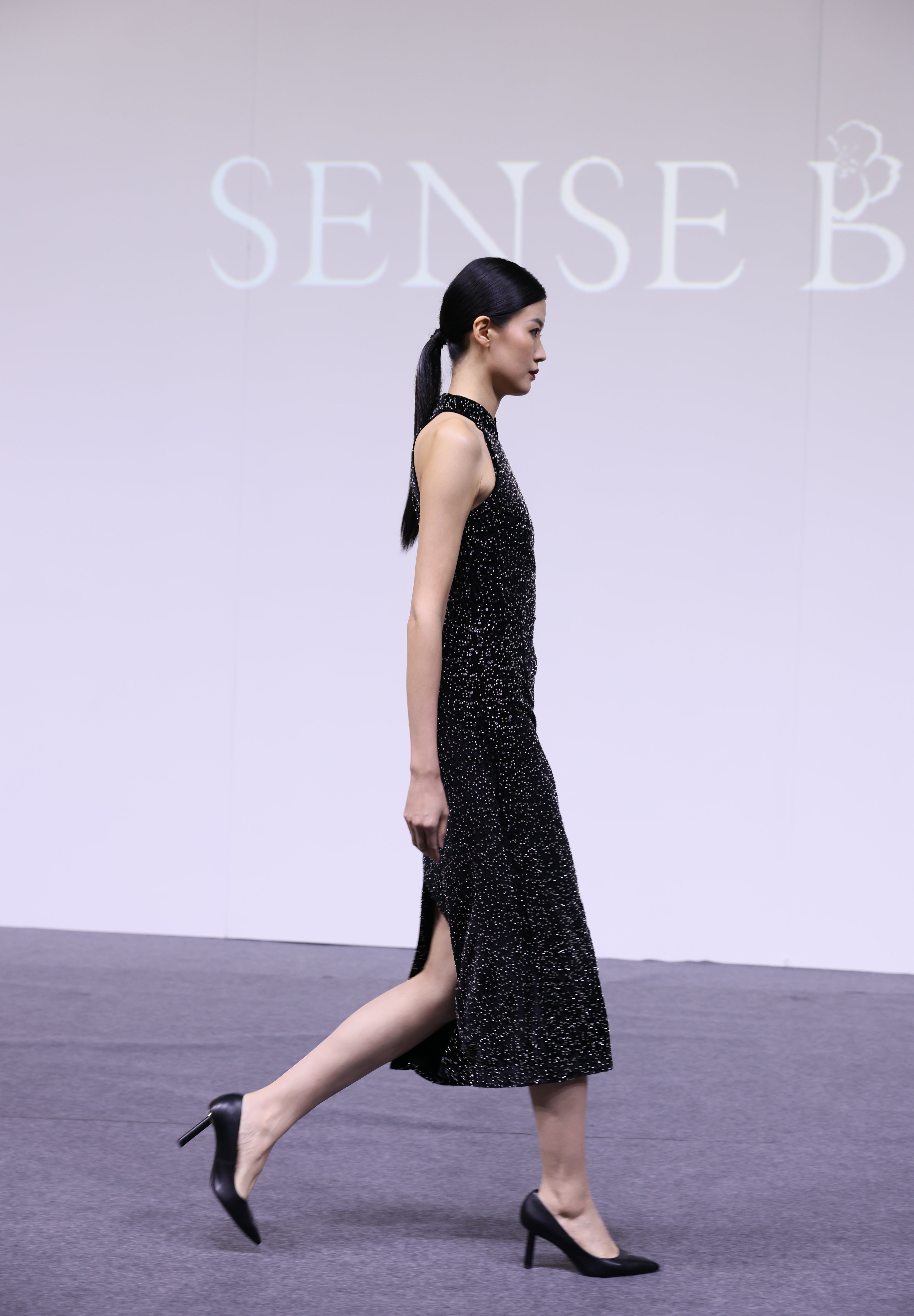 A stunning woman wearing a sophisticated black sequin halter midi dress, featuring a traditional mandarin collar and a shimmering bodycon silhouette, perfect for a modern oriental-inspired evening party look.