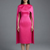 Two professional women wearing sophisticated cape-style dresses: one in a classic black and white monochrome with a thin belt, and the other in a vibrant magenta pink, perfect for a powerful and elegant evening look.