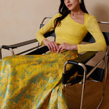 A professional woman wearing a sophisticated high-waisted A-line skirt, featuring a luxurious gold and teal wave pattern jacquard fabric and elegant full-skirt volume for a formal event.