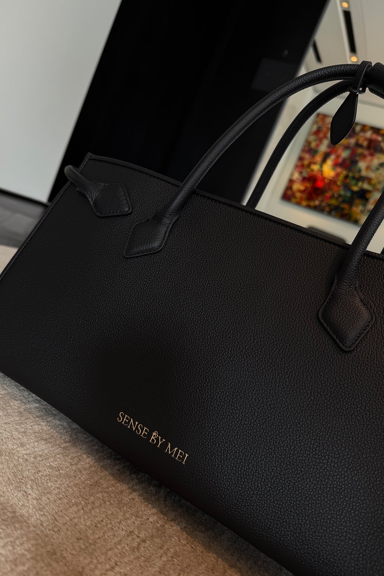 A sophisticated plum purple tote bag crafted from premium pebbled leather, displayed next to a matching shade of luxury lipstick, representing an elegant executive fashion set.