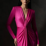A sophisticated woman wearing a vibrant magenta long-sleeve dress, featuring a plunging V-neckline and an elegant knot-front twist at the waist for a stunning evening gala look.