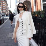 A professional woman wearing a sophisticated cream pinstripe blazer, featuring a double-breasted front with a chic waist-tie belt and notched lapels for a polished old money office look.