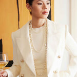 A professional woman wearing a sophisticated cream white double-breasted tweed blazer, featuring elegant gold buttons, a tailored slim fit, and classic flap pockets for a polished executive look.