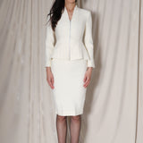 A professional woman wearing a sophisticated cream tweed skirt suit, featuring a tailored jacket with a modern front zipper and an elegant stand collar for a polished executive office look.