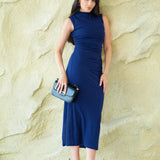 A professional woman wearing a sophisticated navy blue sleeveless midi dress, featuring an elegant high neckline and flattering ruched detailing along the side for a slim-fit executive look.