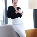 A professional woman wearing sophisticated high-waisted wide-leg pinstripe trousers in charcoal black, featuring a tailored slimming fit for a powerful executive office look.