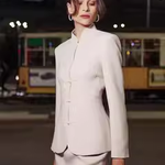 A professional woman wearing a sophisticated beige modern Qipao-inspired skirt suit, featuring a tailored blazer with traditional Chinese frog buttons and a stand collar for an elegant executive office look.