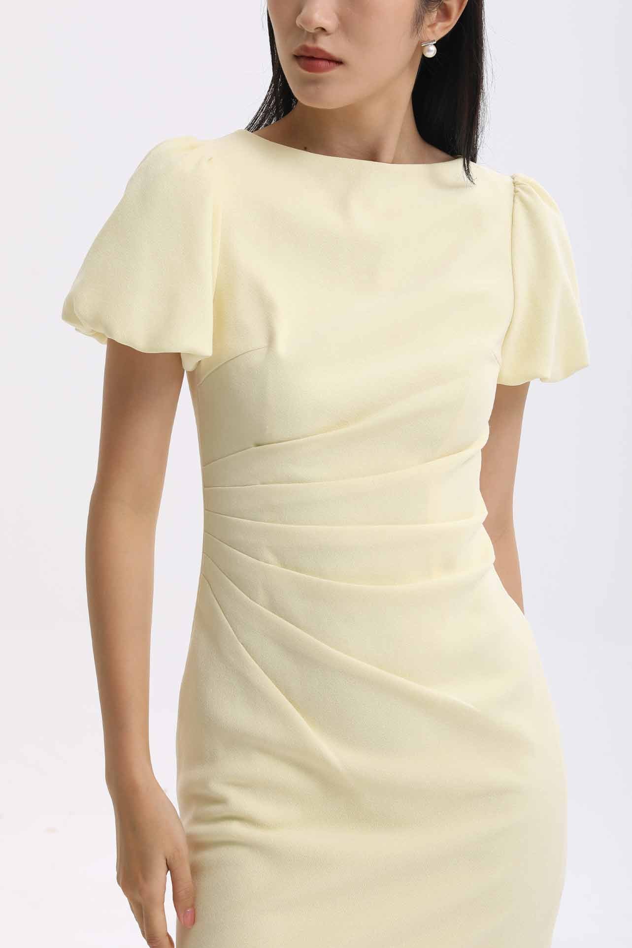 A professional woman wearing a sophisticated pale yellow short-sleeve midi dress, featuring elegant puff sleeves and a slimming ruched waistline for a polished and fresh summer office look.