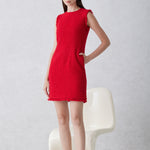 A professional woman wearing a sophisticated vibrant red tweed sleeveless mini dress, featuring a classic round neck, elegant frayed edges, and a slimming black waist belt for a chic holiday or office look.