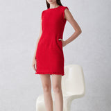 A professional woman wearing a sophisticated vibrant red tweed sleeveless mini dress, featuring a classic round neck, elegant frayed edges, and a slimming black waist belt for a chic holiday or office look.