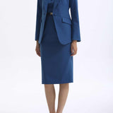 A professional woman wearing a sophisticated royal blue tailored skirt suit, featuring a slim-fit single-button blazer with structured shoulders and a matching midi pencil skirt for a powerful executive office look.