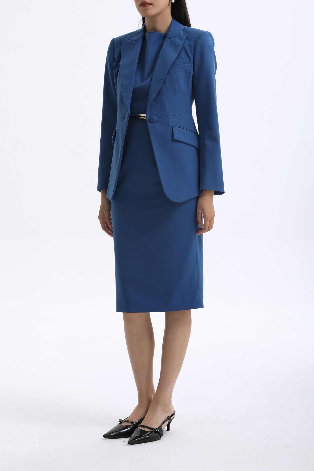 A professional woman wearing a sophisticated royal blue tailored skirt suit, featuring a slim-fit single-button blazer with structured shoulders and a matching midi pencil skirt for a powerful executive office look.