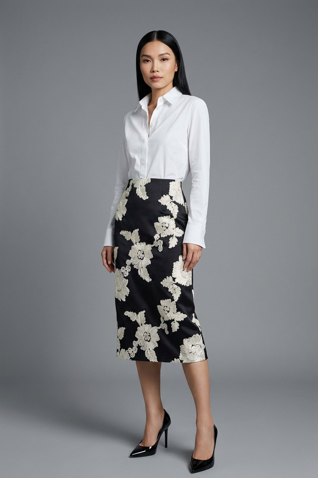 A professional woman wearing a classic crisp white long-sleeve slim-fit blouse with a sharp point collar, styled with a navy blue pencil skirt for a polished executive office look.