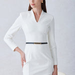 A professional woman wearing a sophisticated solid white long-sleeve sheath dress, featuring an elegant V-neckline and a slim black belt with a gold buckle for a polished executive office look.
