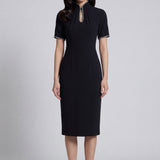 An elegant woman wearing a sophisticated black short-sleeve sheath dress, featuring a traditional mandarin collar with a modern keyhole neckline and delicate beaded trim details for a polished formal look.
