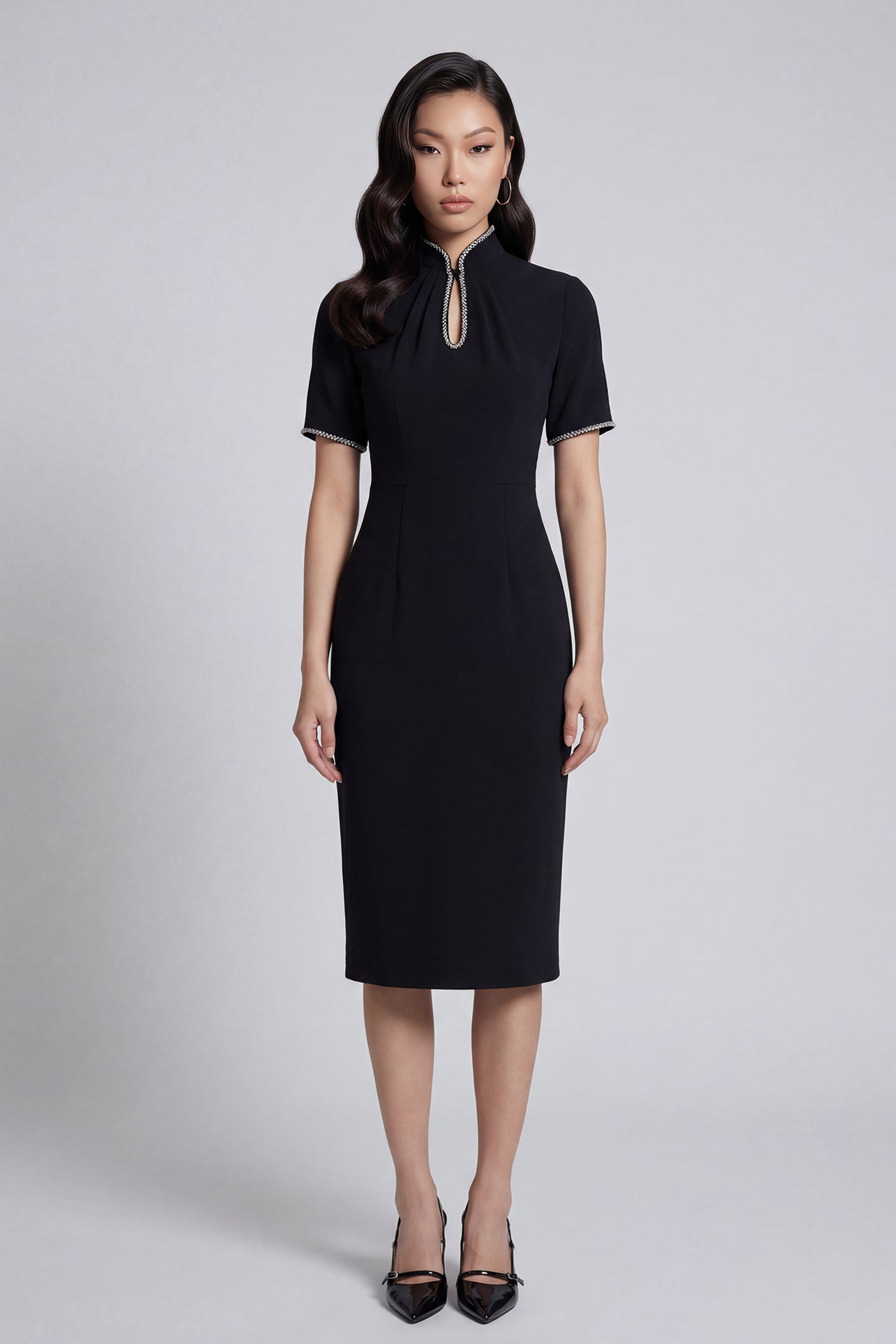 An elegant woman wearing a sophisticated black short-sleeve sheath dress, featuring a traditional mandarin collar with a modern keyhole neckline and delicate beaded trim details for a polished formal look.