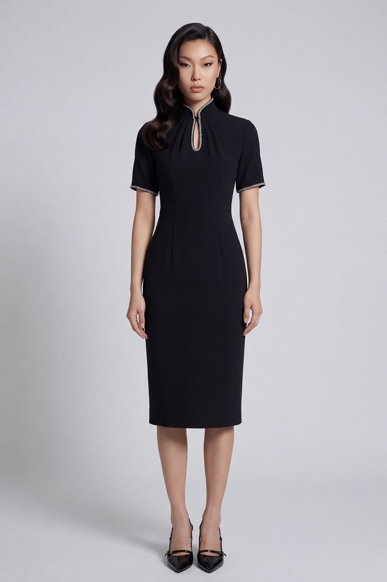 An elegant woman wearing a sophisticated black short-sleeve sheath dress, featuring a traditional mandarin collar with a modern keyhole neckline and delicate beaded trim details for a polished formal look.
