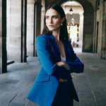 A professional woman wearing sophisticated royal blue high-waisted wide-leg trousers, featuring a tailored loose-fit silhouette for a modern and vibrant executive office look.