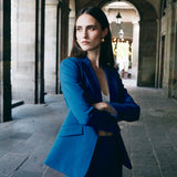 A professional woman wearing sophisticated royal blue high-waisted wide-leg trousers, featuring a tailored loose-fit silhouette for a modern and vibrant executive office look.