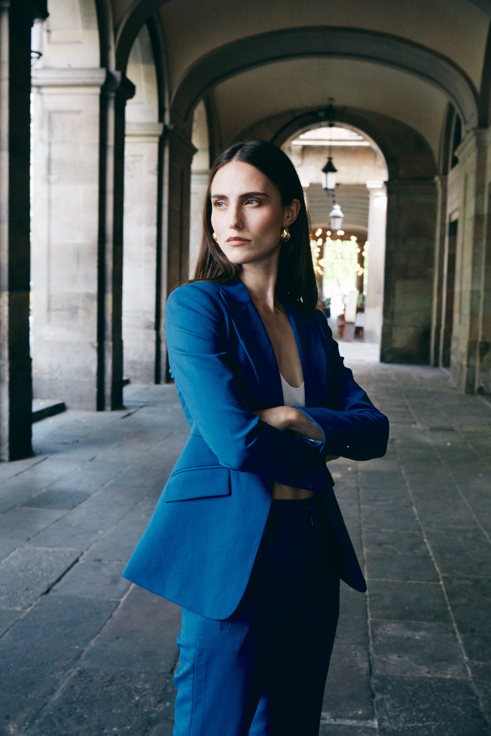 A professional woman wearing sophisticated royal blue high-waisted wide-leg trousers, featuring a tailored loose-fit silhouette for a modern and vibrant executive office look.