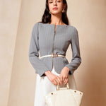 A professional woman wearing a sophisticated grey pinstripe zip-up blazer, featuring a thin white belt with a gold buckle and a tailored slim fit for a modern office look.