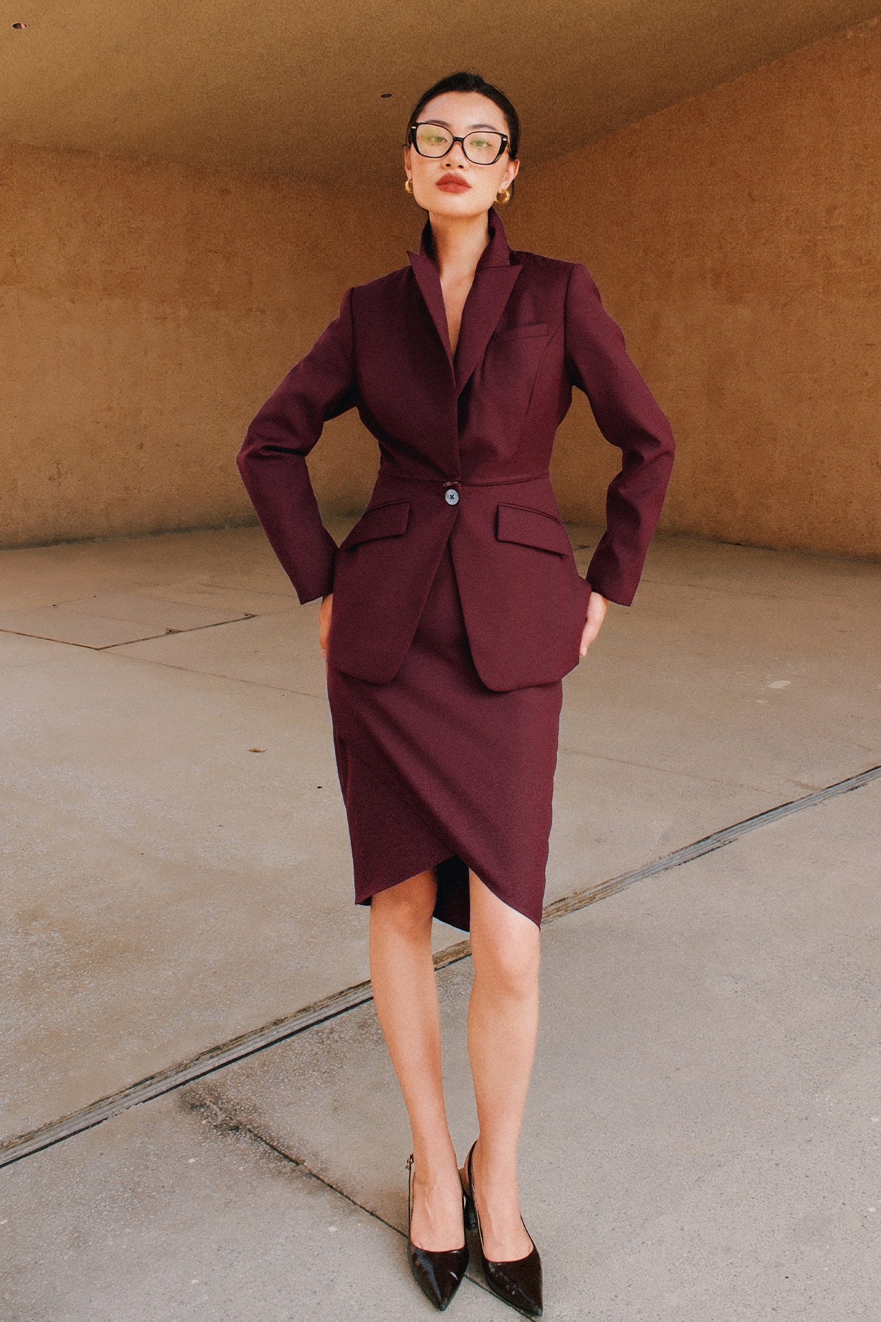 A style comparison of two elegant women's high-waisted pencil skirts featuring an overlapping crossover tulip hemline; shown on the left in deep navy blue paired with a white shirt, and on the right in rich burgundy wine paired with a matching long-sleeve top and suede clutch.