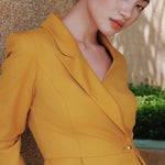A style comparison of two elegant women's skirt suit sets featuring three-quarter sleeve blazers with single-button closure and pleated peplum hems, paired with matching pencil skirts in mustard yellow and deep teal blue.