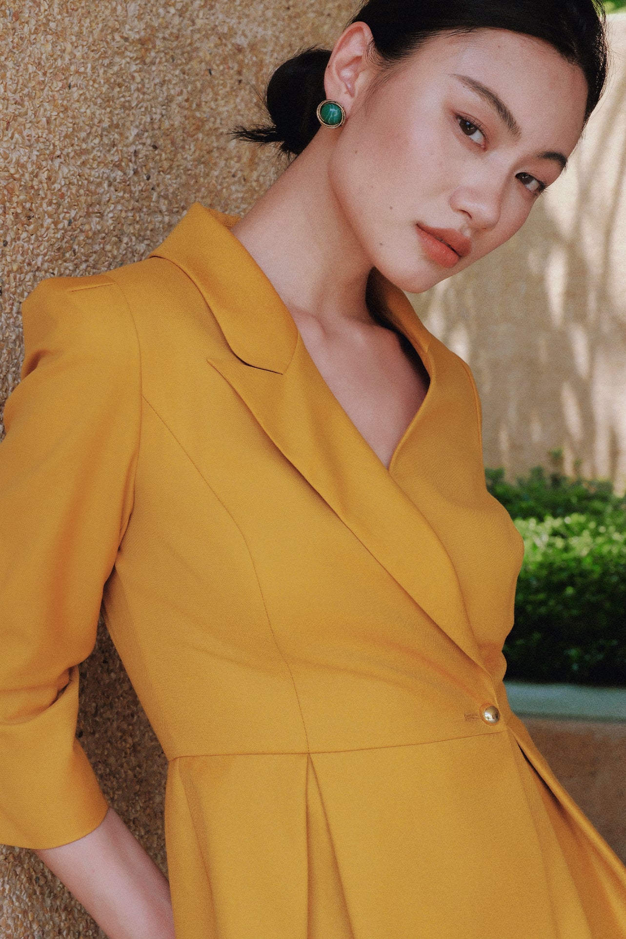 A style comparison of two elegant women's skirt suit sets featuring three-quarter sleeve blazers with single-button closure and pleated peplum hems, paired with matching pencil skirts in mustard yellow and deep teal blue.