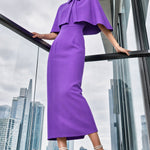 A style comparison of two elegant tailored office sheath midi dresses; the left showcasing a structured vibrant purple dress with a collared capelet sleeve design, and the right featuring a minimalist light grey sleeveless dress with subtle pleated neckline and side pockets.