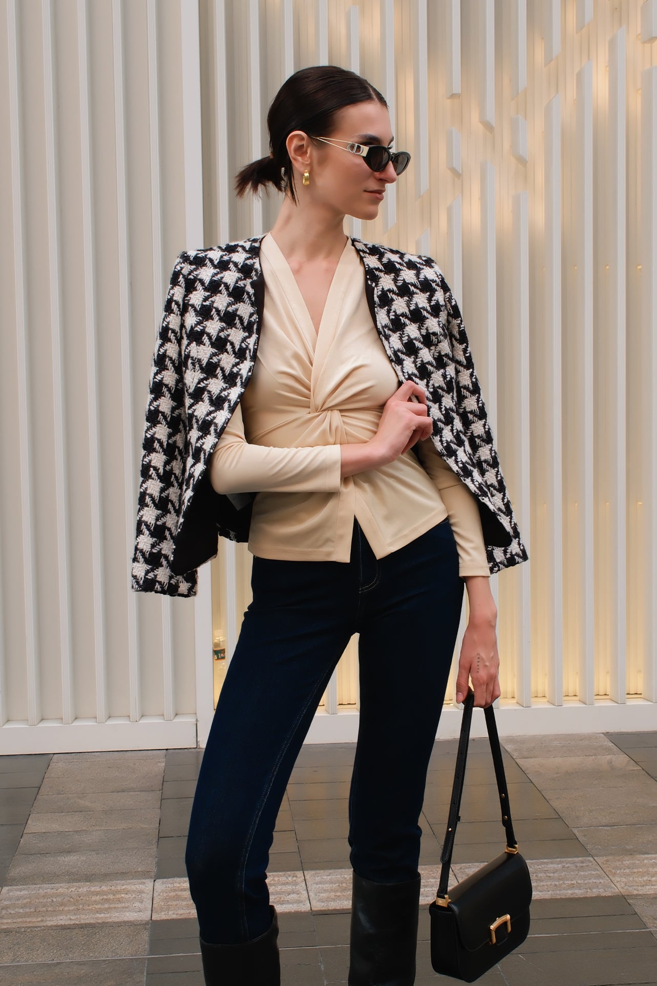 A chic Asian woman modeling an elegant champagne gold long-sleeve top featuring a sophisticated v-neckline and a stylized twist-front knot waist, beautifully paired with high-waisted white trousers.