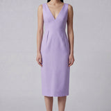 A professional woman showcasing two elegant sleeveless V-neck sheath dresses in classic black and soft lilac purple, featuring functional side pockets and a tailored fit for a polished office look.