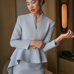 A comparison of three professional women modeling tailored power trouser suits featuring architectural split V-neck jackets with dramatic asymmetrical peplum hems and matching wide-leg trousers in crimson red, deep royal navy, and ice blue.